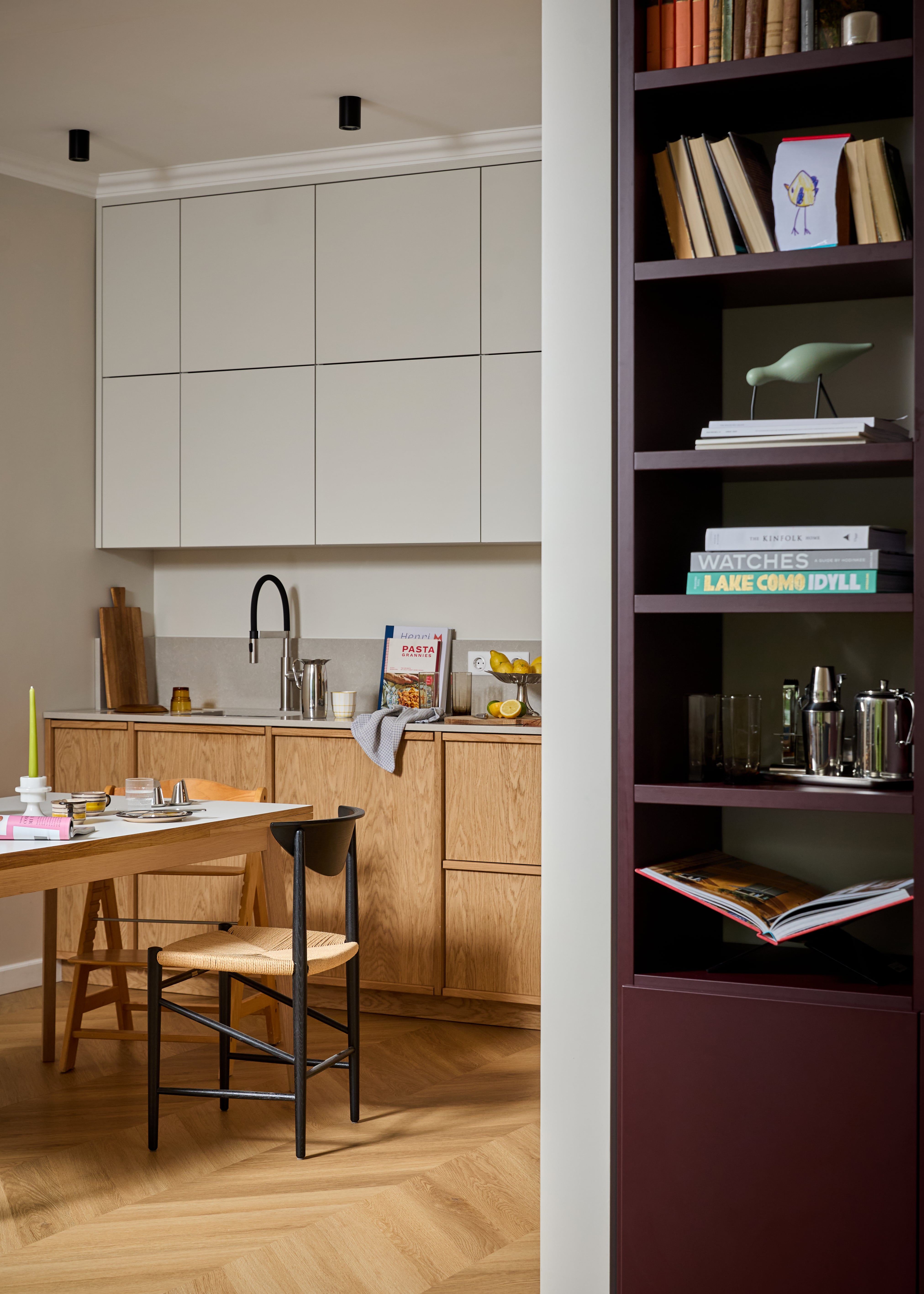 Kitchen with oak cabinetry and burgundy shelving in the D11 apartment